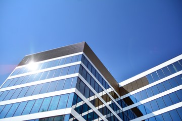 New office building in business center. Wall made of steel and glass with blue sky. 