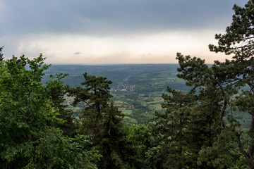 Panorama view over the lush green hills and some villages on the outskirts of Belgrade, Serbia. Moody sky. Nature scenery. Nature background.