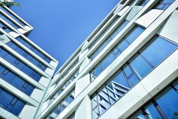 New office building in business center. Wall made of steel and glass with blue sky. 