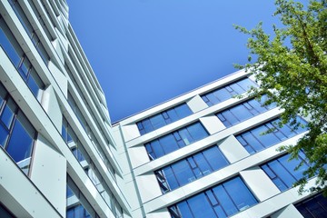 New office building in business center. Wall made of steel and glass with blue sky. 