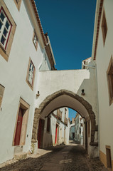 Old whitewashed houses in alley and passageway under arch
