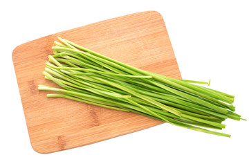 Fresh healthy organic green vegetable garlic chives, chinese chive bunch, green herb on a wooden cutting board isolated on white background with clipping path.