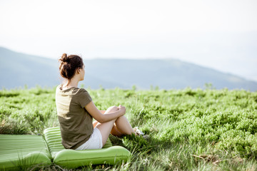 Young woman enjoying landscape view while sitting at the campsite in the mountains