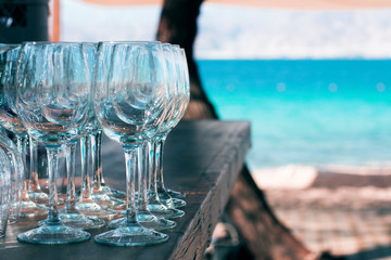 bar counter with empty vine glasses in outdoor natural environment and garden coastline unfocused blurred colorful background