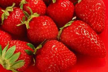 Heap of fresh strawberries on red background