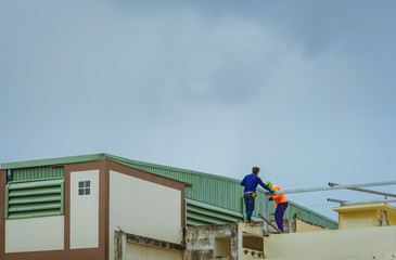 Worker welding the steel part for roof  before it is going to rain.