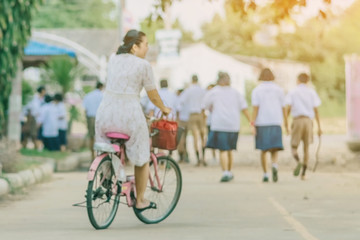 Blur image of female teacher rides bicycle to teach students at classroom.