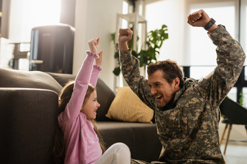 Happy military officer reuniting with his daughter and having fun at home.