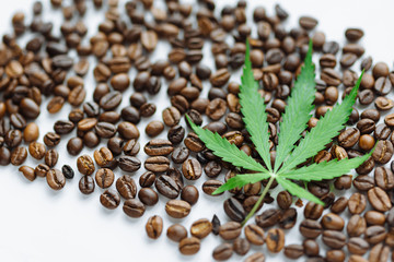 Coffee beans with marijuana leaves background top view.  Green cannabis leaf on coffee beans...