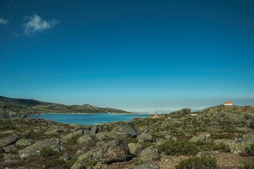 Fototapeta na wymiar Rocky landscape with lake and house on highlands