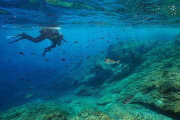 Scuba divers first dive, adult with a child on water surface look at fish underwater, Mediterranean sea, France