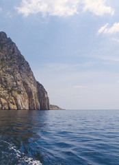 Seascape with a rock on the horizon, waves and clouds. Free space.
