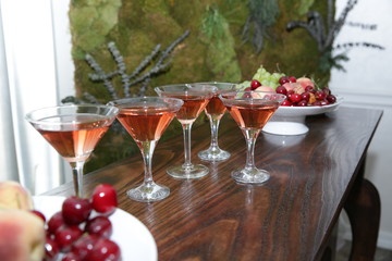 martini glasses of red wine cocktail on a wooden table of a fruit bar in a soft blurred background