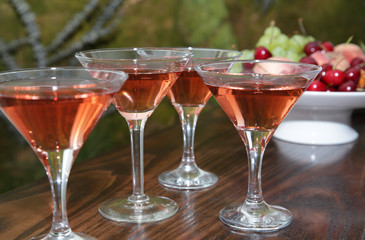  martini glasses of red wine cocktail on a wooden table of a fruit bar in a soft blurred background