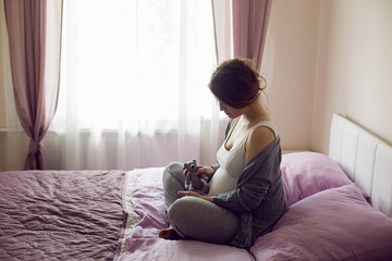 Obraz premium pregnant young girl sitting on bed with toy