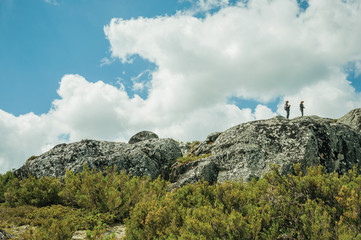 Fototapeta premium Hikers on top of rock formation with bushes