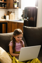 Small girl surfing the Internet on a computer in the living room.