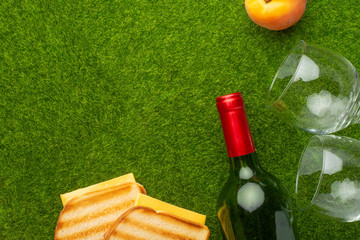 Picnic on the green grass with a bottle of wine and two glasses and peaches and senvichi....