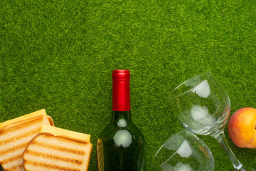 Picnic on the green grass with a bottle of wine and two glasses and peaches and senvichi....