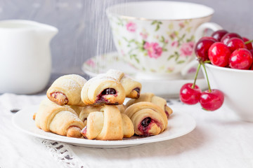 Homemade croissants  with cherry jam and fresh cherries on the table.