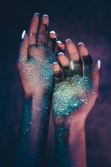 Beautiful young woman dancing and making party with fluorescent painting on her face. Neon facial...