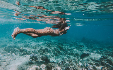 Woman swimming underwater. Concept about vacations and nature. Shot taken with under water action...