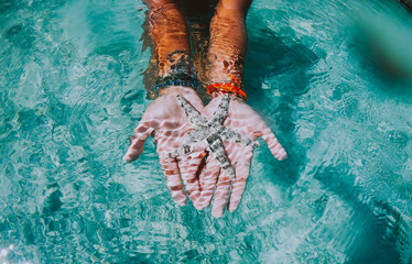 Woman swimming underwater. Concept about vacations and nature. Showing a starfish in her hands