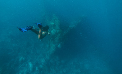 Discovering a japanese ship wreck from second world war. Beautiful woman swimming underwater in a tropical sea. under water shot with action camera. concept about wanderlust travels