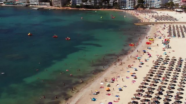 Aerial shot of the beach in Mallorca full of people and umbrellas.