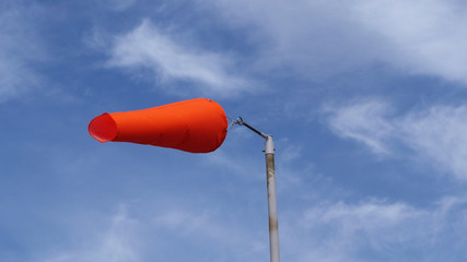 Orange wind sock against blue summer sky