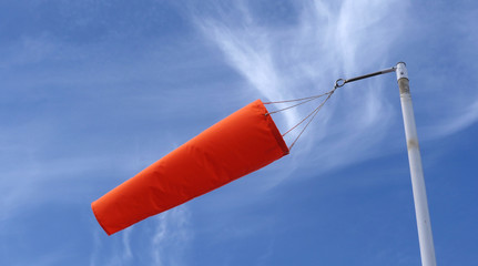 Orange wind sock against blue summer sky