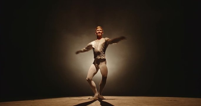 Caucasian male ballet dancer performing on stage, spotted by white light. Young choreographer showing creative performance, isolated on black background 4k footage