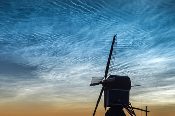 Windmill is silhouetted against a sky full of noctilucent clouds. Photograph was taken in Holland...