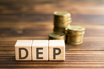 inscription dep wooden cubes with letters, money piles of coins,  wooden background