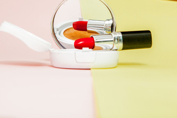 Make up products spilling on to a bright yellow and pink background with copy space