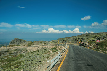 Road over hilly landscape covered by rocks and bushes