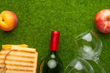 Picnic on the green grass with a bottle of wine and two glasses and peaches and senvichi....