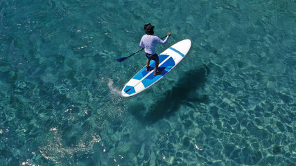 Aerial drone photo of unidentified fit man practising Stand Up Paddle or SUP in tropical exotic...
