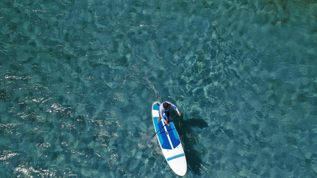 Aerial drone photo of unidentified fit man practising Stand Up Paddle or SUP in tropical exotic mediterranean bay with turquoise sea