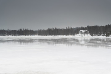 Rural house with reflections on Finnish winter lake