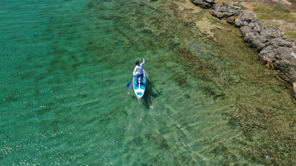 Aerial drone photo of unidentified fit man practising Stand Up Paddle or SUP in tropical exotic...