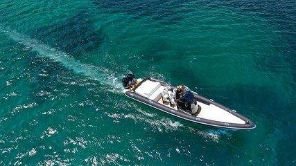 Aerial photo of inflatable rib speed boat cruising in high speed deep blue sea of Mykonos island, Cyclades, Greece