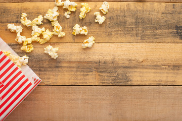 packaging with popcorn on a wooden background. sprinkled popcorn. rest and entertainment. background