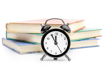 Alarm clock with books on white background.