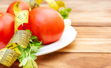 Plate with tomatoes, green onion, parsley and measuring tape on the table. Space for text.