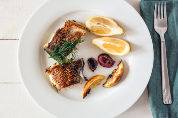 Grilled dorado fish served with lemon and red onion.