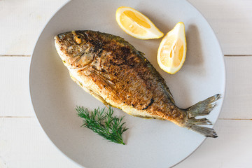 Grilled dorado fish served with lemon on plate