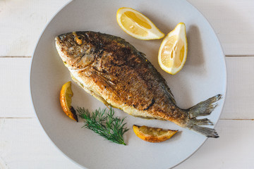 Grilled dorado fish served with lemon on plate