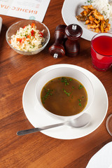 Hot autumn chicken soup as a part of set menu, placed on a wooden table with other males on background