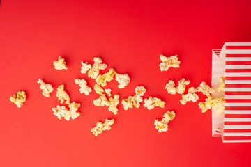 Popcorn packaging on a bright red background. sprinkled popcorn. rest and entertainment. Flat lay